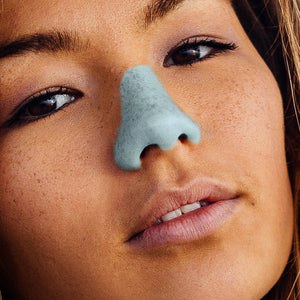 beautiful young woman with trendy, affordable, colorful, cruelty-free, reef-safe spf formula on nose